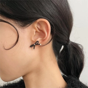 Detail of 925 sterling silver pearl bow earring worn by a model in soft lighting
