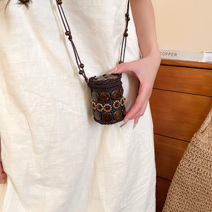 Close-up of a handmade coconut shell mini crossbody bag with ethnic beaded flowers