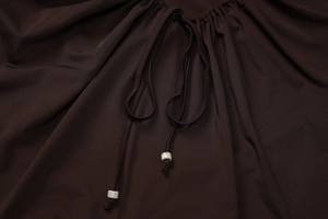 Gros plan d'un haut marron avec dentelle découpée et perles effet marbre blanc