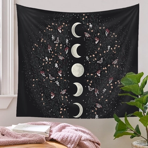 Detail of bohemian moon phase tapestry with moth and botanical patterns on a white wall
