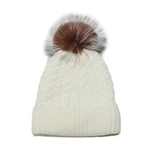 Detail of knit beanie with large fluffy faux fur pompom and thick texture in cream
