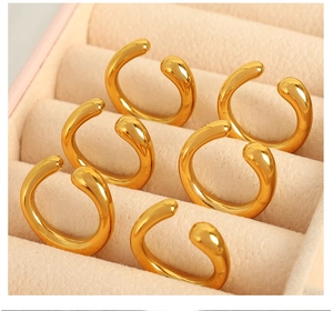 Close-up of six gold minimalist C-shaped clip-on earrings in a pink velvet jewelry box