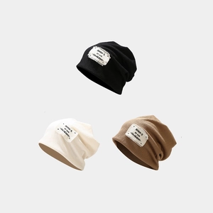 Three trendy knitted slouchy beanies in black, cream, and brown with vintage patch labels