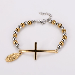 Detail of beaded religious bracelet with golden cross and virgin mary oval pendant