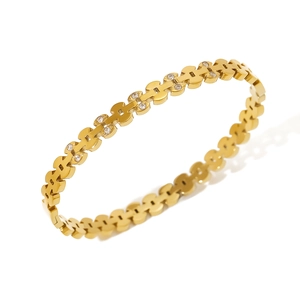 Detailed macro view of gold-plated bangle with H-shaped links and zircon stone inlays