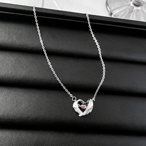 Macro detail of heart wing pendant with pink zircon on a black leather tray