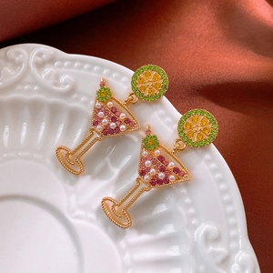 Detail shot of lemon cocktail glass earrings with pink crystals and pearls on silk