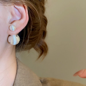 Detail view of 18k gold plated earrings with brushed texture and black polka dots