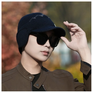Detail of dark blue winter knit hat with ear flaps and short brim on a male model