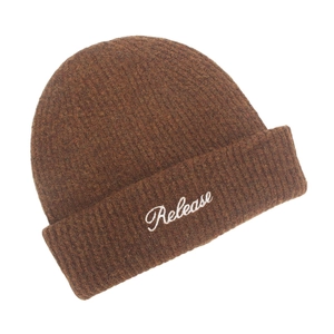 Close-up of brown knit beanie featuring white Release embroidery and ribbed texture
