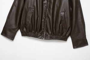 Detail of dark brown faux leather bomber jacket showing hem, zipper, and pocket texture