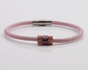 Detail of pink braided rope bracelet with rose gold clasp and purple teardrop stone