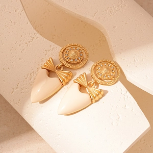 Gros plan sur des boucles d'oreilles vintage à nœud et cœur avec placage or et émail blanc