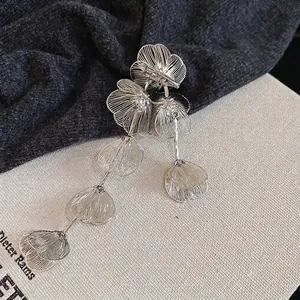 Elegant silver flower brooch with hollow mesh petals and long tassels on fabric