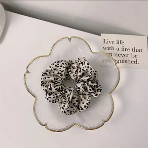 Detail of soft black and white leopard print scrunchie on a decorative glass plate