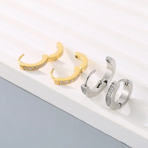Close-up of gold and silver titanium steel hoop earrings set with sparkling zircon stones