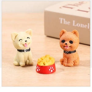 Close-up of cute resin puppy figurines with a red food bowl in a miniature garden landscape