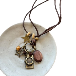 Retro wax cord necklace with wood beads and vintage bronze camera pendant on ceramic plate