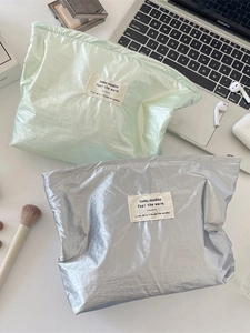 Metallic silver and mint green makeup organizer bags in a high-angle desktop lifestyle setup