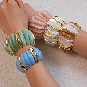 Macro detail of multicolored acrylic resin bracelets with polished gold plating on wrist