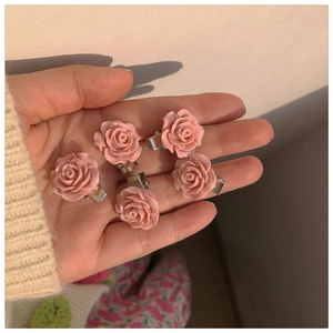 Close-up of five pink camellia hair clips with silver metal duckbill clips held in hand