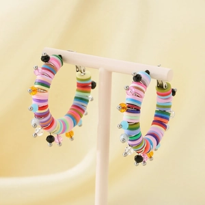 Détail de créoles bohèmes avec perles en argile colorées et breloques en cristal