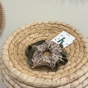 Dettaglio dell'elastico verde militare a pois con fiocco in pelle rosa su cesto