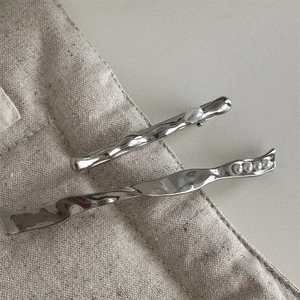 Detailed view of two silver metal hair clips with irregular hammered texture and pearls