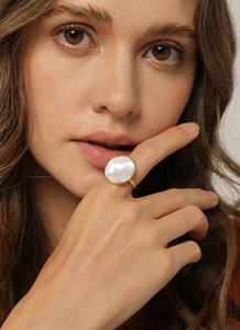 Minimalist gold ring featuring a large round white mother-of-pearl shell on a female finger