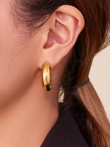 Macro view of 18k gold plated chunky hollow C-shaped hoop earrings on a model ear