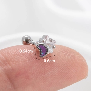 Macro detail of star and moon cartilage stud with purple zircon on a finger