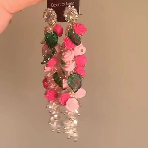 Close-up of pink rose floral tassel earrings with green leaves and crystal beads