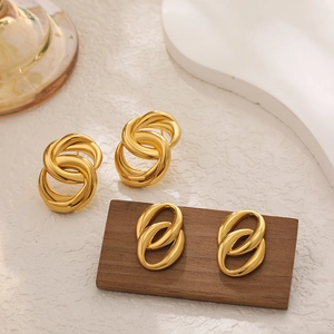 Detailed view of 18K gold double oval entwined earrings on a wooden display stand