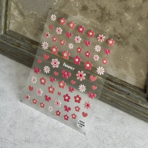 Close-up of 3D embossed nail stickers featuring pink flowers and heart patterns