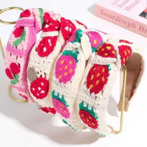 Close-up of four hand-knitted headbands with 3D strawberry embroidery and texture