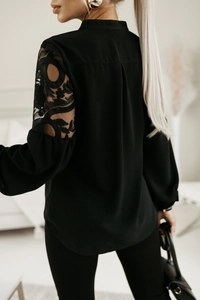 Dettaglio ravvicinato del ricamo in pizzo floreale nero sulle maniche della camicia donna