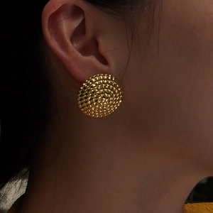 Elegant gold round stud earrings with textured surface worn by a model in deep light
