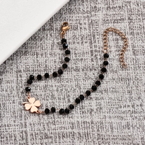 Detail of black beaded bracelet with rose gold clover charm and adjustable lobster clasp