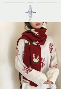 Detail of red Christmas scarf featuring white reindeer patterns and soft knit texture