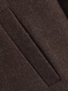 Close-up of deep brown wool fabric showing detailed pocket stitching and premium texture