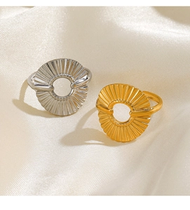 Detailed close-up of 18K gold and silver sunburst texture rings on silk fabric