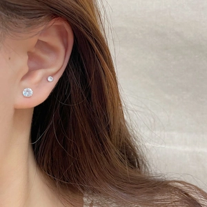 Minimalist silver stud earrings set with sparkling zircon stones worn on ear