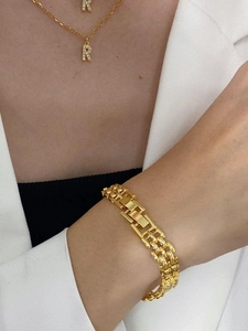 Close-up of gold chain necklace with diamond-encrusted R-letter pendant and link bracelet