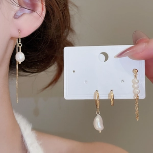 Detail view of gold pearl earrings set featuring a long tassel threader and stud earrings
