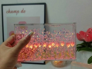Detail of DIY tulip night light with pink sequins and glowing LED string in acrylic frame