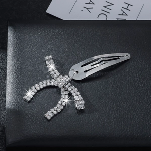 Chic silver bow metal hair clip with rhinestones on a black leather background