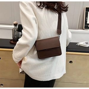 Close-up of deep brown leather textured rectangular crossbody bag with wide shoulder strap