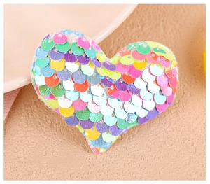 Gros plan d'une pince à cheveux en forme de cœur avec des paillettes irisées colorées