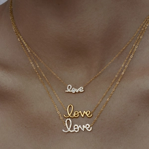 Close-up of layered gold necklaces with love letter pendant and sparkling rhinestones