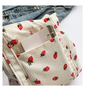 Detail of cream corduroy tote bag with strawberry prints and clear PVC front pocket